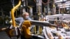 FILE - GM workers use human assistance automation to weld vehicle doors at the General Motors assembly plant during the COVID-19 pandemic in Oshawa, Ontario, March 19, 2021.