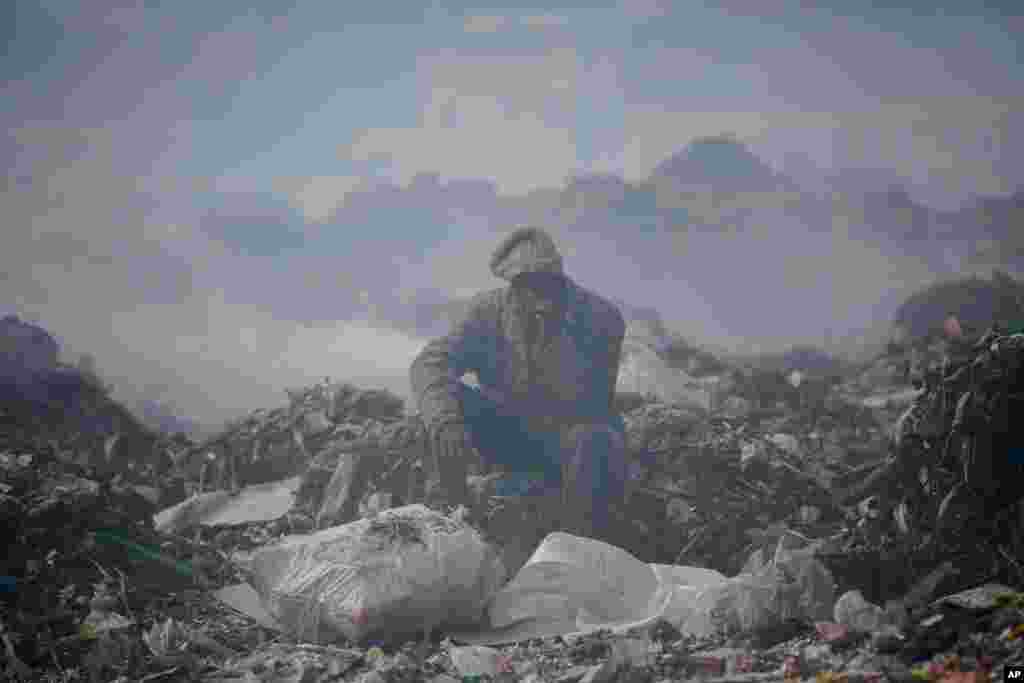 A man who scavenges recyclable materials for a living rests on a mountain of garbage amidst smoke from burning trash at Dandora, the largest garbage dump in the capital Nairobi, Kenya, Sept. 7, 2021.