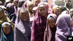 Internally displaced Somali children line up with containers in hand to receive food aid at a food distribution center, in Mogadishu, Somalia, (File Photo - March 15, 2011)