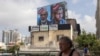 A man walks past a billboard displaying portraits of Hamas leaders Ismail Haniyeh, left, and Mohammed Deif and with the slogan 