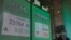 A man wearing a face mask walks past a bank electronic board showing the Hong Kong share index at Hong Kong Stock Exchange, June 1, 2020. 