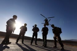 FILE - American soldiers wait on the tarmac at an airfield in Logar province, Afghanistan, Nov. 30, 2017.