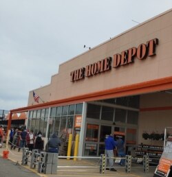 Customers practice 'social distancing' while waiting in line to get into a Home Depot in Alexandria, Virginia, that is limiting the number of people inside the store.
