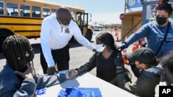 East Hartford High School senior Sudeen Pryce, right, center, receives a shot at a mass vaccination site at Pratt & Whitney Runway in East Hartford, Conn., Monday, April 26, 2021. (AP Photo/Jessica Hill)