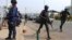 Security personnel take positions as police officers run along the convoy of Nigeria's President Goodluck Jonathan after a People's Democratic Party (PDP) National Executive Council meeting in Abuja, Jan. 16, 2014.