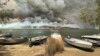 Perahu-perahu diamankan ke pesisir pantai sementera kebakaran lahan membara di Boats are pulled ashore as smoke and wildfires rage behind Lake Conjola, Australia, Jan. 2, 2020.