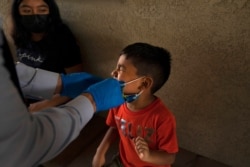 Shahir Sanchez, 5, grimaces as Dr. Neal Schwartz collects a nasal swab sample for COVID-19 testing at Families Together of Orange County Aug. 26, 2021, in Tustin, Calif.