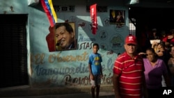 Personas se paran frente a un mural con las fotografías del expresidente Hugo Chávez y su sucesor Nicolás Maduro, en el barrio 23 de Enero de Caracas, en julio de 2023.