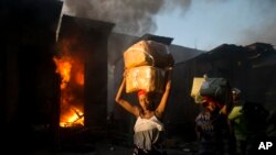 Vendors carry salvaged merchandise from the burned ruins of the Guerite Market that was engulfed in flames in Port-au-Prince, Haiti,vJan. 14, 2020. 