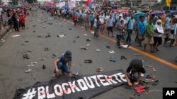Protesters scatter pairs of slippers and shoes to symbolize victims killings in the so-called war on drugs of President Rodrigo Duterte as others march towards the Lower House to coincide with Duterte's second state of the nation address Monday, July 24, 2017.