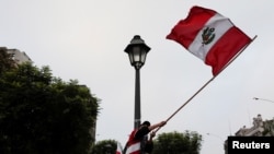 A supporter of Peru's presidential candidate Pedro Castillo waves a Peruvian flag the day after a runoff election, in Lima, Peru, June 7, 2021. 