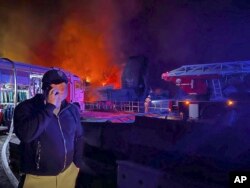 13일 우크라이나 남부 크름반도(크림반도) 세바스토폴의 조선소에서 대규모 화재가 발생한 가운데 현장 관계자가 휴대전화로 통화하고 있다.