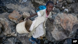 FILE: Kenyan child Irene Wanzilla, 10, lugs a bucket of broken rocks after hammering them alongside her mother and siblings at a Nairobi-area quarry, Sept. 29, 2020. The children were pulled from school after their mother lost her job due to the Cornavirus pandemic. 