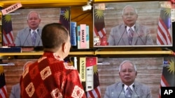 Seorang pelanggan menyaksikan tayangan langsung pengumuman oleh PM Malaysia, Najib Razak, di sebuah toko alat-alat listrik di Kuala Lumpur, Malaysia, hari Jumat, 6 April 2018 (foto: AP Photo/Sadiq Asyraf)