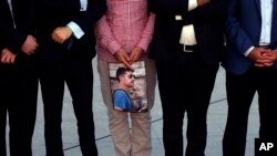 People hold a photograph of James Foley, the freelance journalist killed by the IS group, during a memorial service in Irbil, 350 kilometers (220 miles) north of Baghdad, Iraq, Sunday, Aug. 24, 2014.