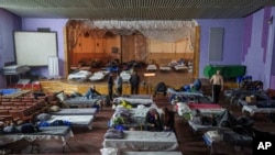 People sit on beds after evacuation from the frontline at a center for displaced people in Pavlohrad, Ukraine, Feb. 1, 2024. 