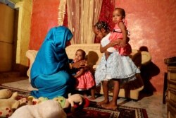 FILE - Youssria Awad plays with her daughters in their home, in Khartoum, Sudan on June 14, 2020. She refuses to carry out female genital mutilation on them.
