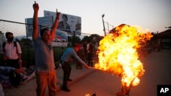 A Nepalese policeman tries to put off the burning effigy of Indian Prime Minister Narendra Modi during a protest by Nepalese youth in Kathmandu, Nepal, Sept. 30, 2015.