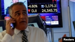 A trader works on the floor following the closing bell as a screen shows the Dow Jones Industrial Average on the New York Stock Exchange, (NYSE) in New York, Feb. 5, 2018.