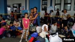 FILE - A Venezuelan migrant woman poses for a picture with her children, while they wait to have their documents processed at the Ecuador-Peru border, on the outskirts of Tumbes, Peru, June 17, 2019.