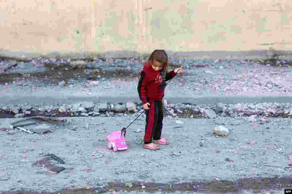 Seorang anak perempuan Palestina menarik mainannya di jalan yang dipenuhi puing-puing di Jabalia di Jalur Gaza utara, di tengah perang antara Israel dan kelompok Hamas Palestina. (AFP)&nbsp;