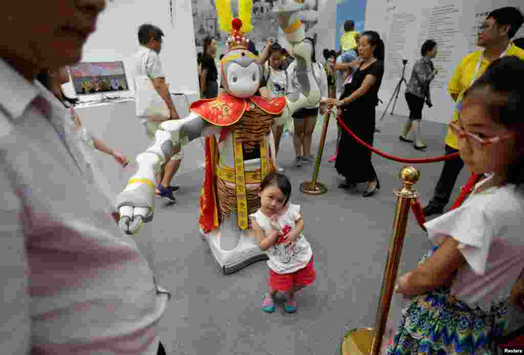 ژست دختر بچه در کنار ربات کپی شده از شخصیت فیلم پادشاه میمون در کنفرانس جهانی ربات در چین &nbsp;