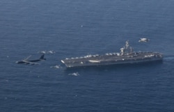 FILE - The USS Abraham Lincoln aircraft carrier and a U.S. Air Force B-52H Stratofortress conduct joint exercises in the Arabian sea, June 1, 2019.