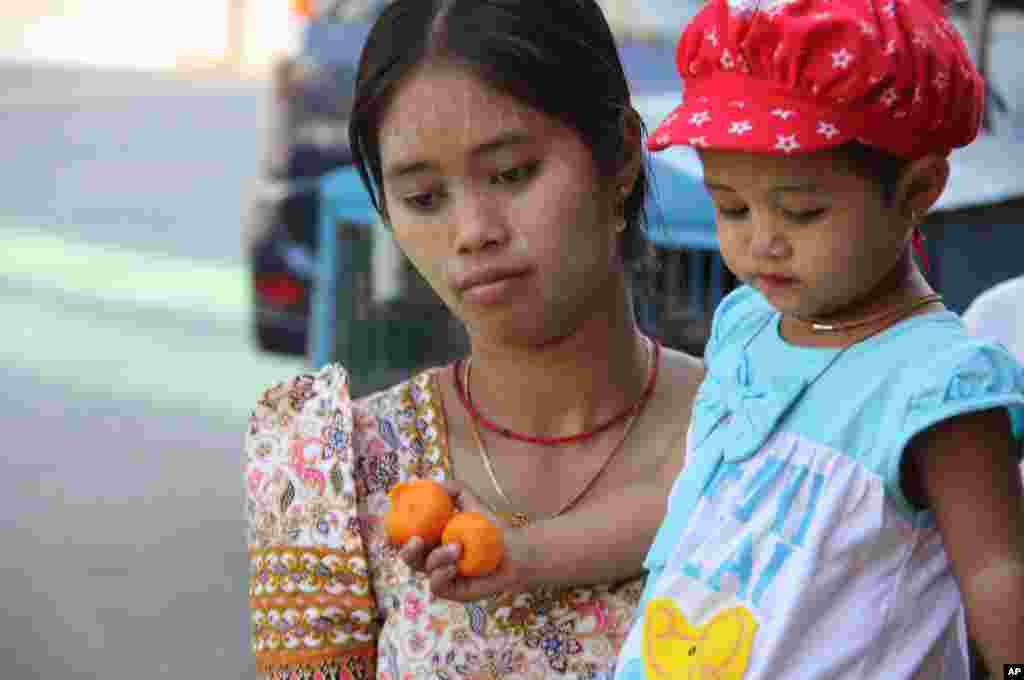 A woman and child walk in Rangoon. (VOA-D.Schearf)