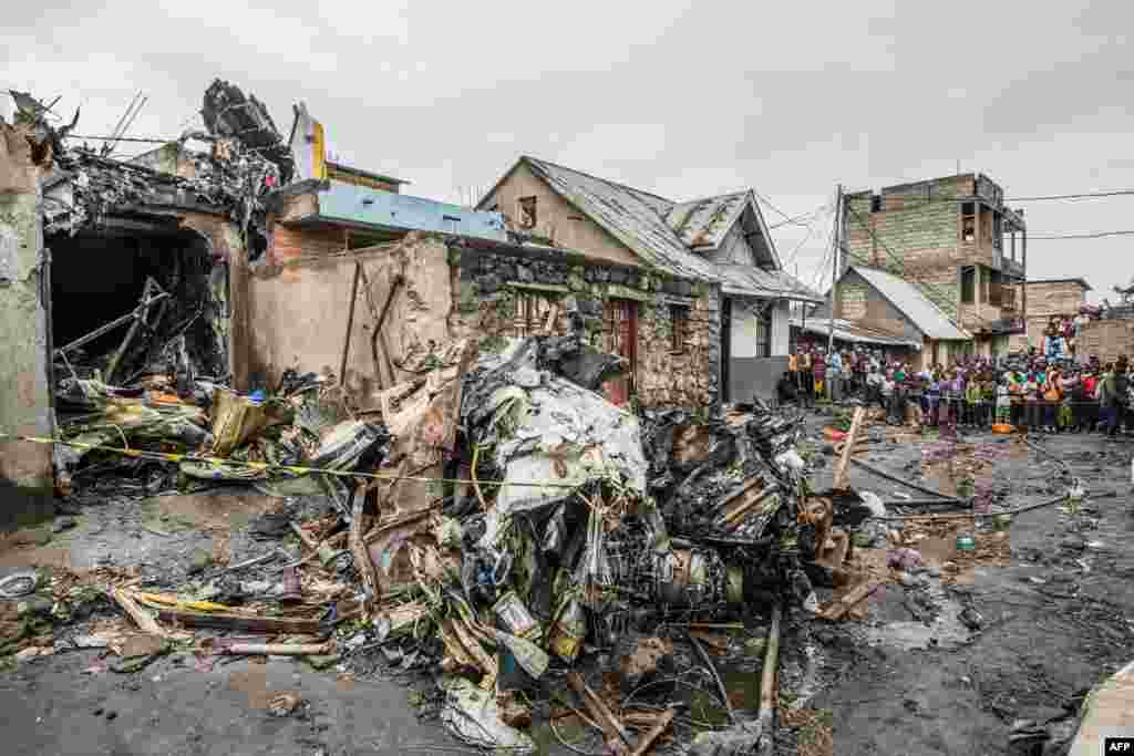 Residents gather to look at the wreckage of a small aircraft that crashed in a densely populated area is seen in Goma on the East of the Democratic Republic of Congo. At least 29 people were killed.