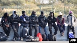 FILE - Young migrants wait to board a bus leaving for a reception centre, in Calais, on Oct. 28, 2016, following a massive operation to clear the "Jungle" migrant camp.