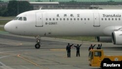Ground crew members wave to passengers on board the TransAsia Airways airplane which is the first cross-strait flight of the day from Taiwan to Shanghai, China, at the Taipei Songshan Airport in this 2008 file photo. (REUTERS/Pichi Chuang )