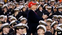 President Donald Trump applauds a flyover while seated with Navy midshipman during halftime of the Army-Navy NCAA college football game, Dec. 14, 2019, in Philadelphia, Pennsylvania.