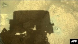 FILE - The shadow of the Perseverance Mars rover is cast next to its first hole drilled in a rock, in this image acquired on August 6, 2021 (Sol 164) and released by NASA. The rock was too crumbly to collect, but a sample was collected in September.