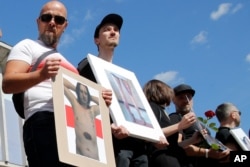 People hold pictures of a protesters beaten by police during a rally in Minsk, Belarus, Aug. 15, 2020.
