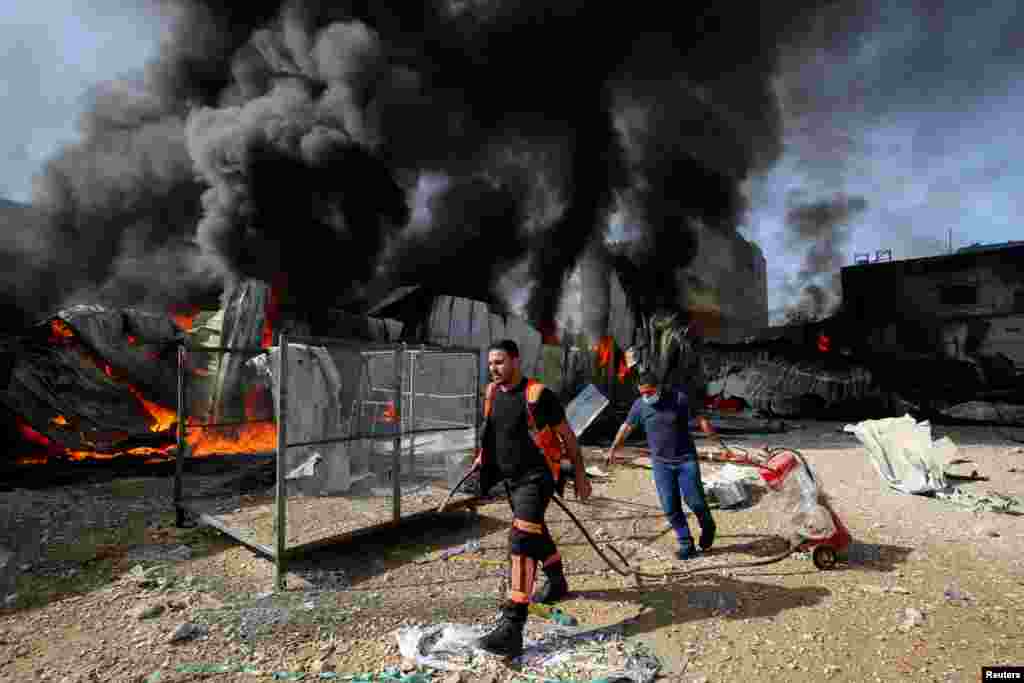 Un bombero palestino camina mientras participa en los esfuerzos para apagar un incendio en una f&#225;brica de esponjas despu&#233;s de que fue alcanzada por proyectiles de artiller&#237;a israel&#237;, seg&#250;n testigos.