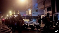 Police officers stand guard outside a disco in Lima, Peru, Aug. 23, 2020. Officials said over a dozen people died in a stampede at a disco after a police raid to enforce the country's lockdown during the coronavirus pandemic.