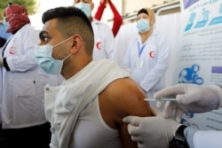 A Palestinian health worker is vaccinated against COVID-19 after the delivery of doses from Israel, in Bethlehem, in the Israeli-occupied West Bank, Feb. 3, 2021.