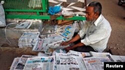 A vendor arranges newspapers with headlines about Supreme Court's verdict on a disputed religious site claimed by both majority Hindus and Muslim in Ayodhya, in Ahmedabad, India, Nov. 9, 2019. 