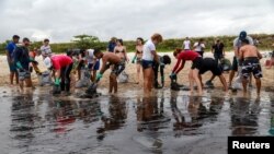 People work to remove an oil spill on Suape beach in Cabo de Santo Agostinho, Pernambuco state, Brazil, Oct. 20, 2019.