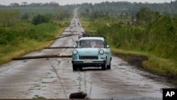 FILE - People drive along a road littered with fallen power lines after the passing of Hurricane Rafael in San Antonio de los Banos, Cuba, Nov. 7, 2024. 