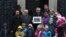 Labour peer Alf Dubs (C) poses with protestors as he delivers a petition to Number 10 Downing Street opposing the closure of a government scheme to bring unaccompanied child refugees to Britain from Europe, in London, Feb. 11, 2017. 