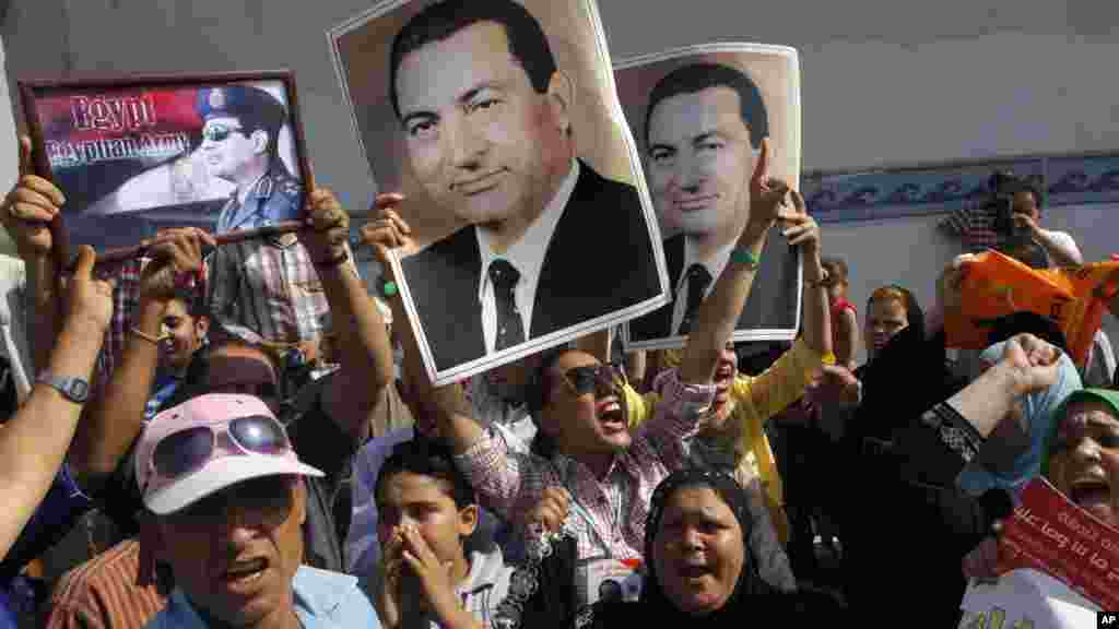 Supporters of former Egyptian President Hosni Mubarak hold his posters and a poster of Egyptian Army Chief Lt. Gen. Abdel-Fattah el-Sissi, left, in front of Tora prison in Cairo, Aug. 22, 2013.