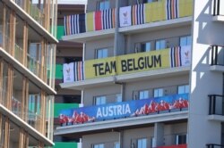 FILE - Signs from the Belgian and Austrian teams hang on the apartment building hosting Olympics participants at the Athletes Village, in Tokyo, July 18, 2021.