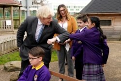 British Prime Minister Boris Johnson elbow bumps with the Head Girl during his visit to St Mary's CE Primary School, ahead of reopening of the primary and secondary schools across England planned for March 8, in Stoke-on-Trent, March 1, 2021.