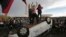 Protesters stand on an overturned car outside Congress where senators later voted in support of a spending cap bill in Brasilia, Tuesday, Nov. 29, 2016.