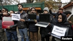 FILE - Kashmiri journalists display laptops and placards during a protest demanding restoration of internet service, in Srinagar, Nov. 12, 2019.