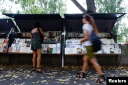 People walk past traditional street booksellers or bouquinistes along the banks of the River Seine in Paris, France, August 18, 2022. REUTERS/Sarah Meyssonnier
