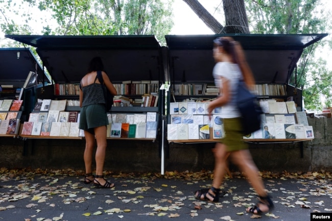 People walk past traditional street booksellers or bouquinistes along the banks of the River Seine in Paris, France, August 18, 2022. REUTERS/Sarah Meyssonnier