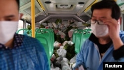 Des livreurs d'une épicerie à l'intérieur de leur bus à Wuhan, l'épicentre de l'épidémie du nouveau coronavirus, dans la province du Hubei en Chine, le 5 mars 2020.