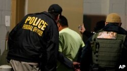 FILE - U.S. Immigration and Customs Enforcement agents escort a target to lockup during a raid in Richmond, Va., Oct. 22, 2018. President Donald Trump has ordered immigration enforcement officials to conduct a roundup of migrants, June 23, 2019.